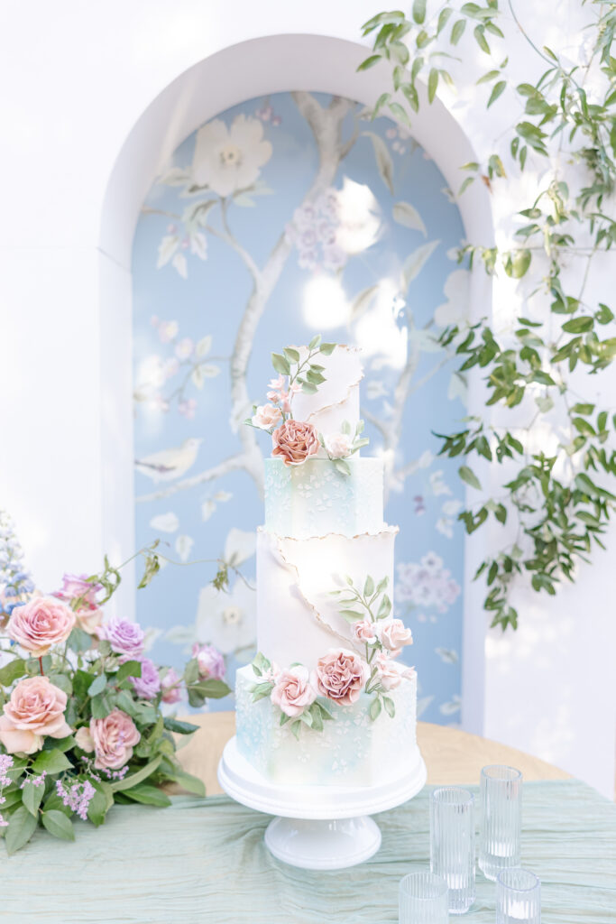 Photo of luxury wedding cake in pastel colors with light blue custom print arch backdrop